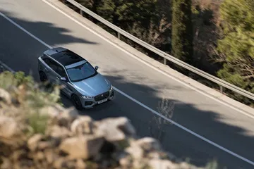 Vista lateral del Jaguar F-PACE en movimiento, mostrando su elegancia y dinamismo.