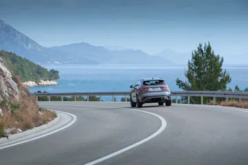 Vista trasera y lateral del Jaguar F-PACE en carretera de montaña.