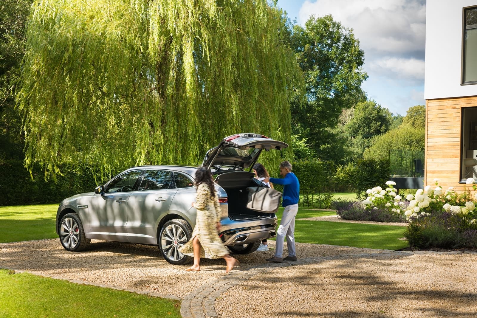 Vista trasera y lateral de un Jaguar F-PACE mientras se carga equipaje en el maletero