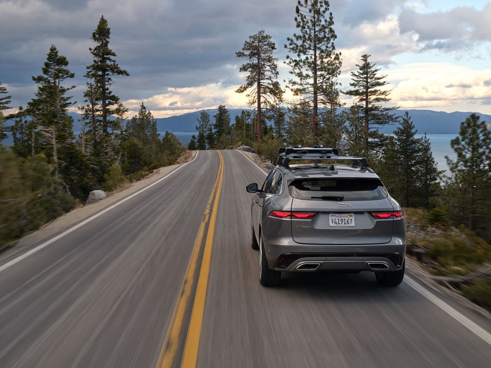 Vista trasera y lateral del Jaguar F-PACE en carretera con paisaje natural al fondo