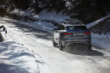 Vista trasera y lateral de un Jaguar F-PACE en condiciones invernales.