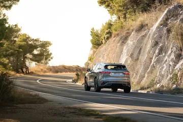 Vista dinámica del Jaguar F-PACE tomando una curva en carretera.