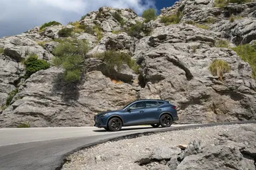 Vista lateral del CUPRA Formentor en un entorno de montaña, destacando su diseño y entorno.