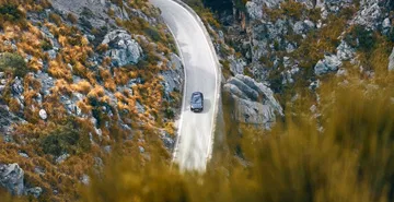 Vista aérea del CUPRA Formentor serpenteando una carretera de montaña.