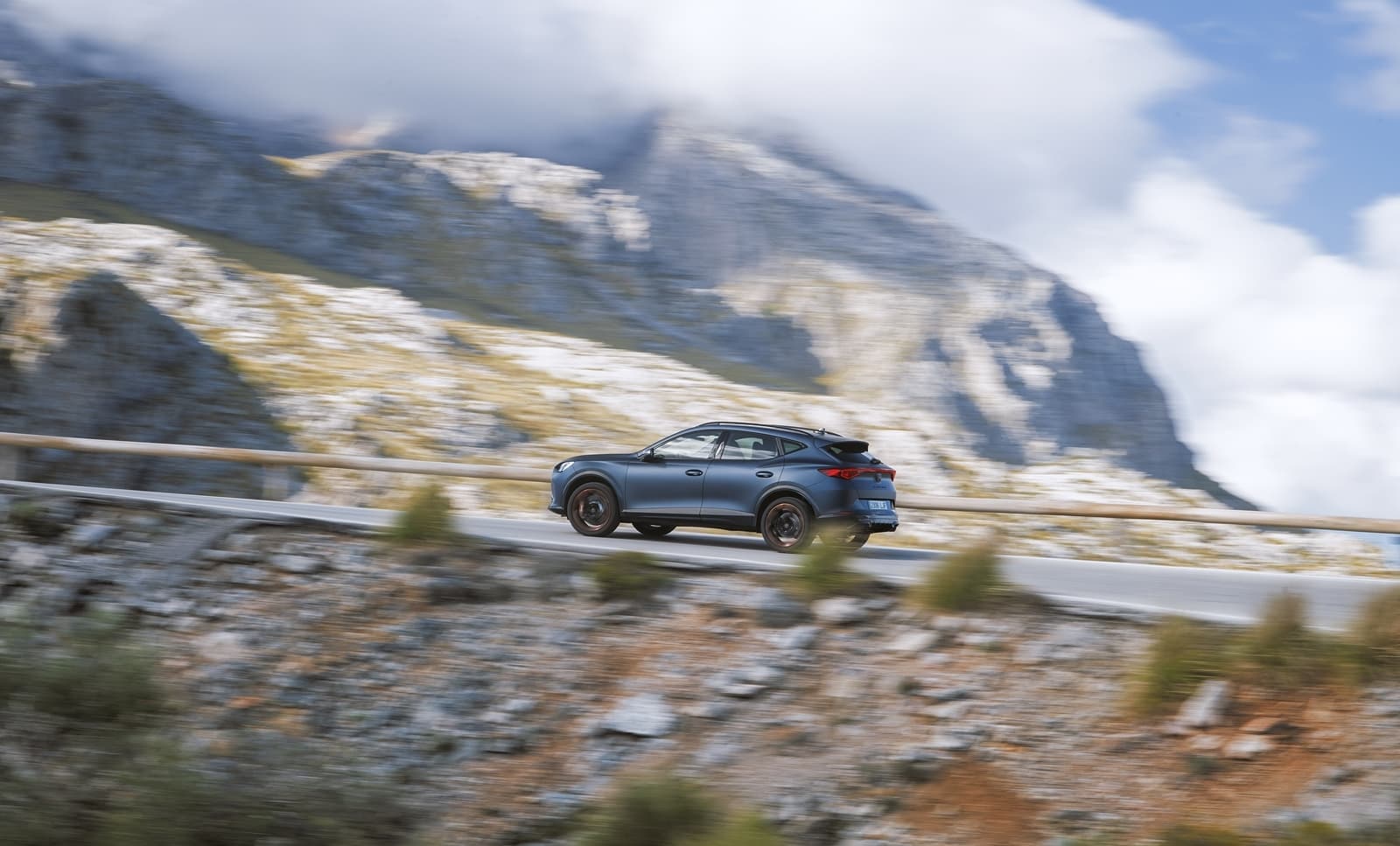 Vista dinámica del CUPRA Formentor en carretera de montaña, destacando su línea lateral.