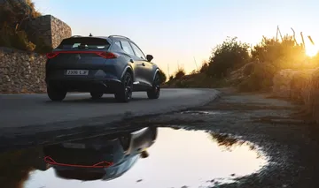 Vista trasera y lateral del CUPRA Formentor con un reflejo en charco al atardecer