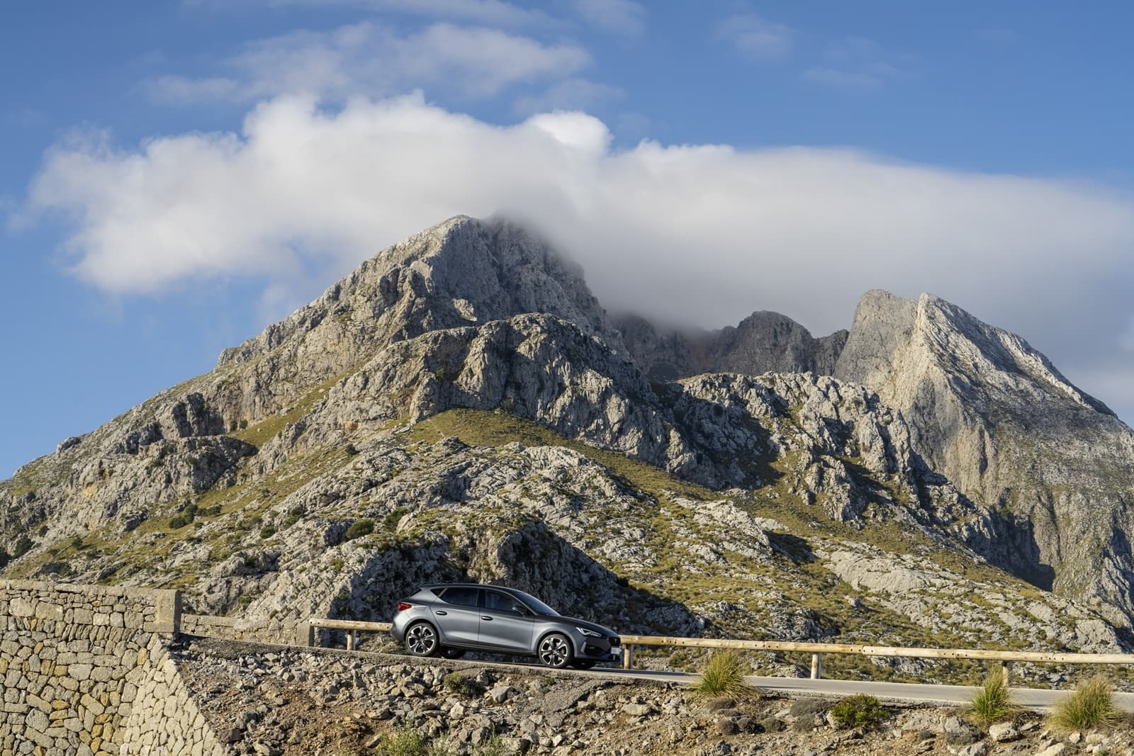 Vista lateral del CUPRA León rodando por una carretera de montaña.