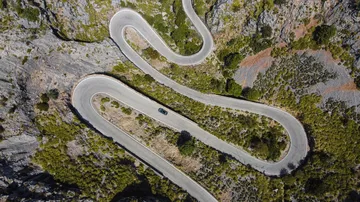 Vista aérea del CUPRA León trazando curvas en carretera de montaña.