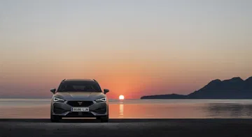 Vista frontal del CUPRA León con un atardecer de fondo que realza sus líneas modernas.
