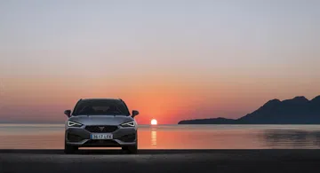 Frente del CUPRA León capturado con un atardecer de fondo.