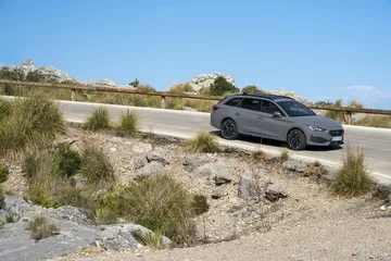 Vista lateral del CUPRA León en carretera, realzando su perfil deportivo.