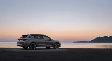 Vista lateral del CUPRA León con un atardecer de fondo, realzando su diseño dinámico.
