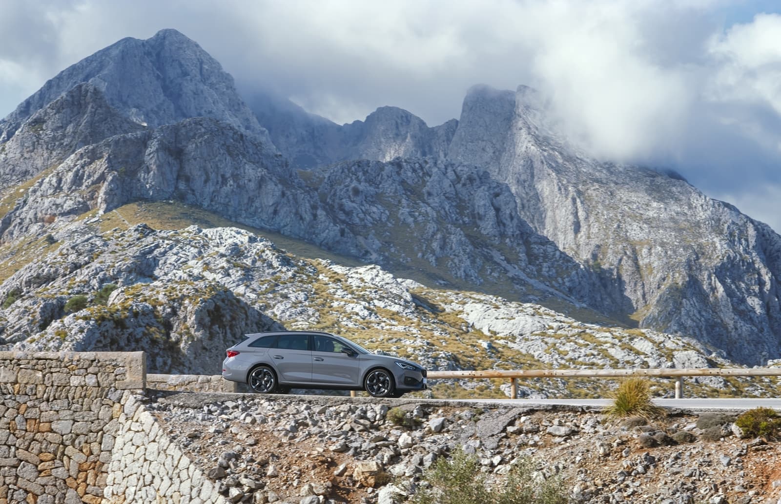 Vista lateral del CUPRA León contrastando con paisaje montañoso.