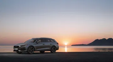 Vista lateral del CUPRA León al atardecer, destacando su diseño dinámico.