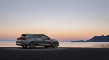 Vista lateral del CUPRA León con atardecer de fondo