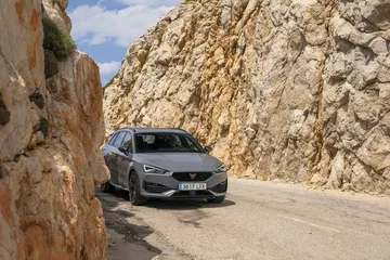 Vista lateral del CUPRA León estacionado en carretera de montaña.
