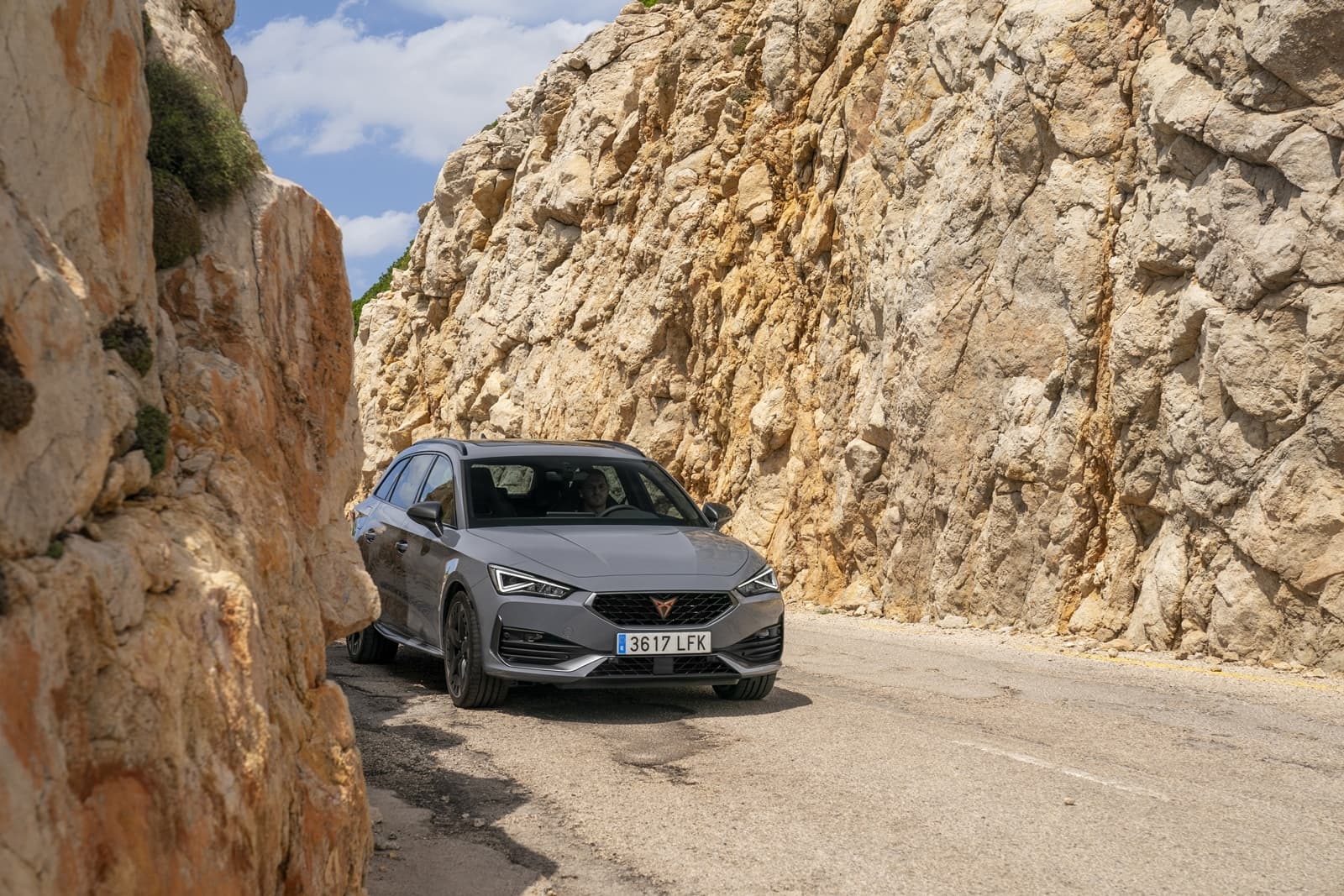 Vista lateral del CUPRA León estacionado en carretera de montaña.
