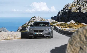 Vista frontal-lateral del CUPRA León en carreteras montañosas.