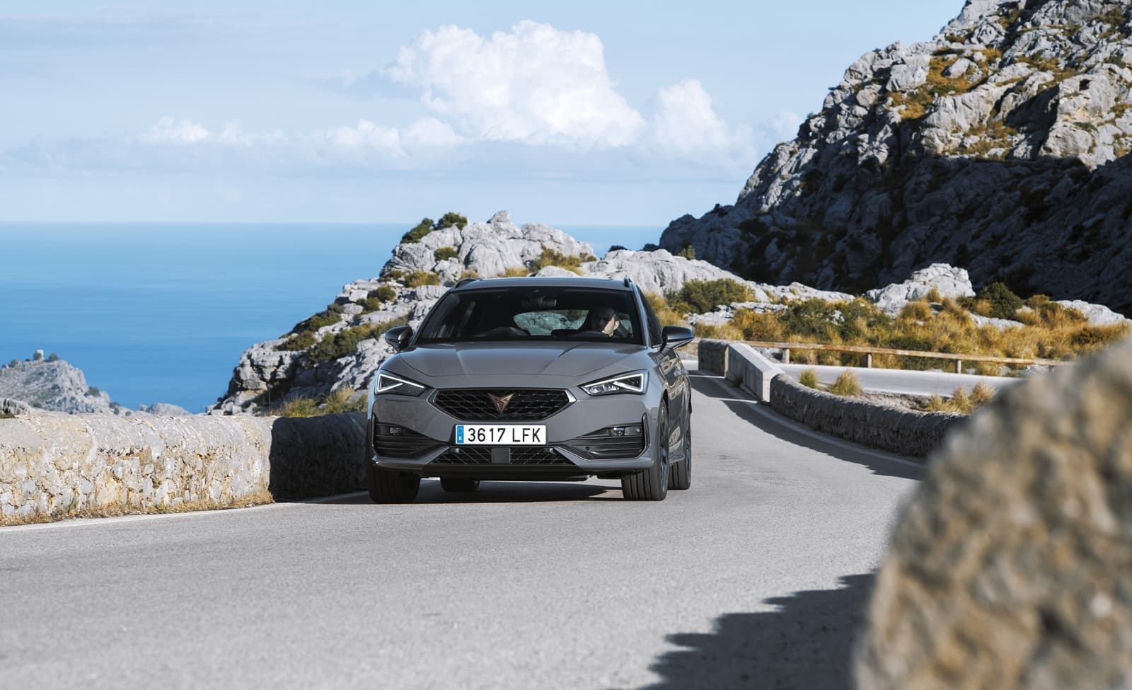 Vista frontal-lateral del CUPRA León en carreteras montañosas.