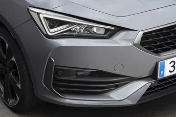 Vista cercana del faro delantero y parrilla del CUPRA León, destacando su diseño agresivo.