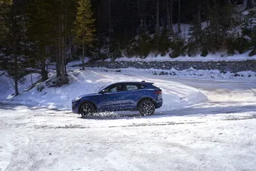 Vista lateral del Jaguar E-PACE rodando sobre un manto de nieve.