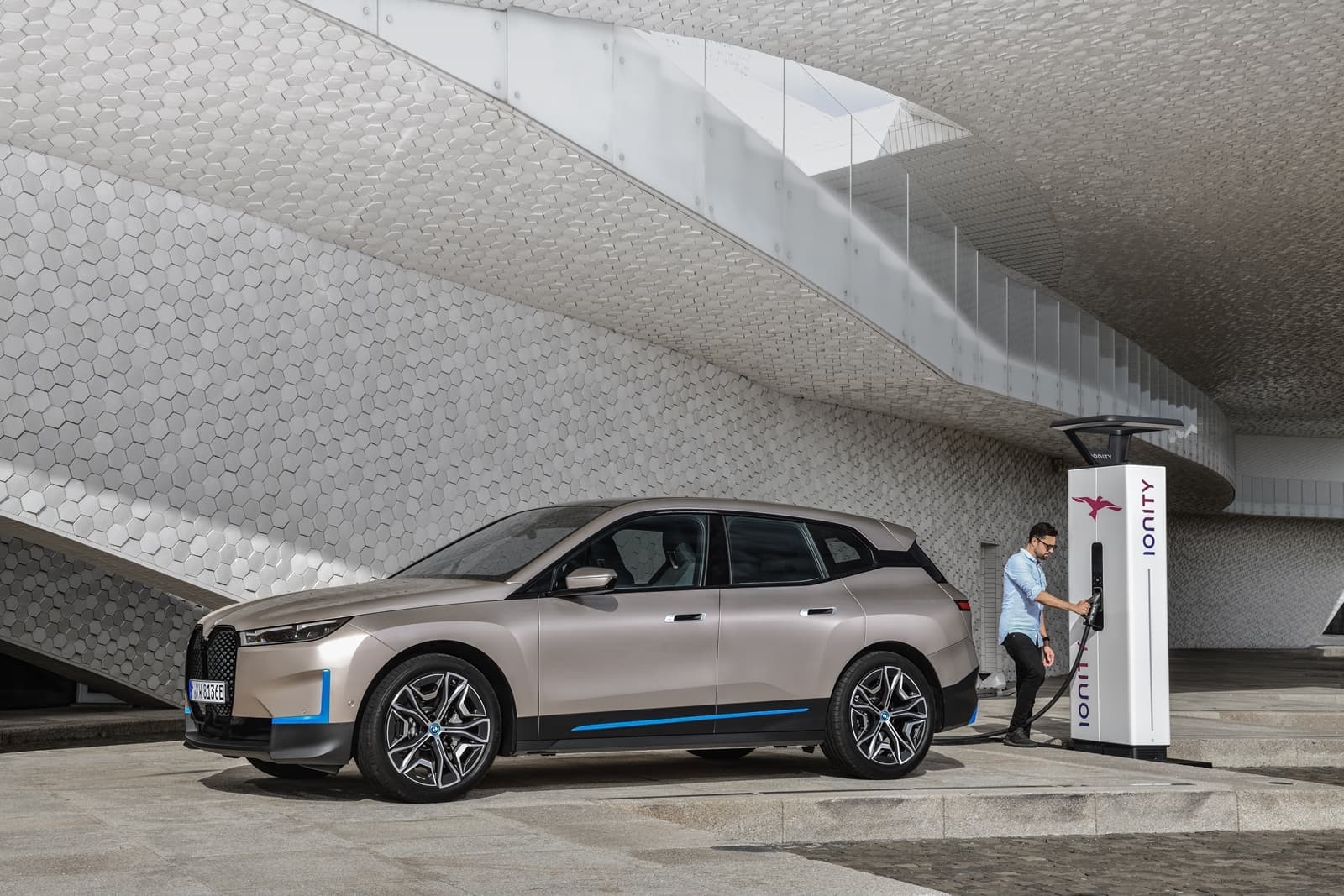 Vista lateral del BMW iX cargando en una estación de carga eléctrica