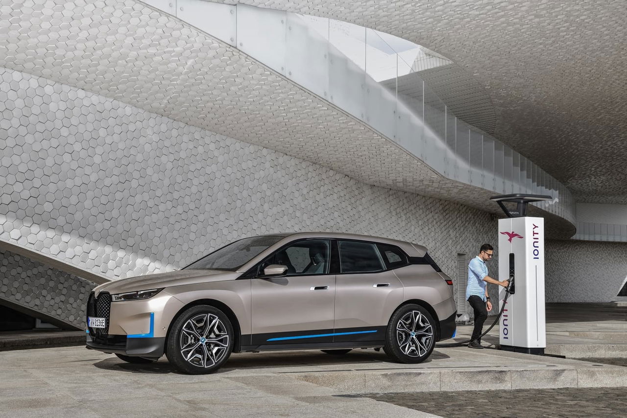 Vista lateral del BMW iX cargando en una estación de carga eléctrica