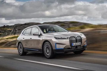 Vista dinámica del BMW iX en movimiento destacando su diseño lateral.