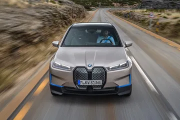 BMW iX capturado en dinámica, resaltando su imponente parrilla frontal