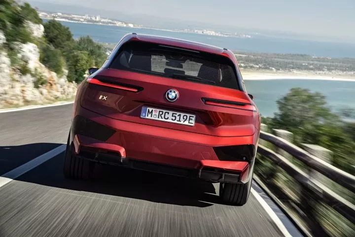 Vista dinámica de la trasera y lateral del BMW iX en carretera.