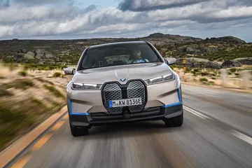 Vista frontal dinámica del BMW iX en movimiento, destacando su parrilla distintiva.