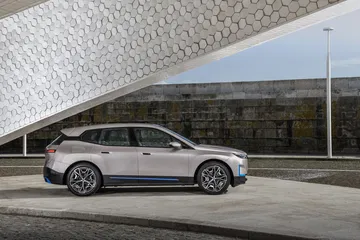 Vista lateral del BMW iX destacando su diseño aerodinámico y llantas futuristas.
