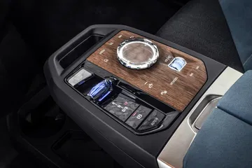 Consola central del BMW iX con acabados de madera y controles táctiles.