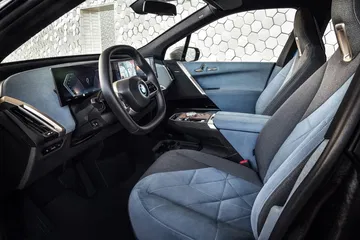 Vista lateral del elegante interior del BMW iX, mostrando asientos y tablero.