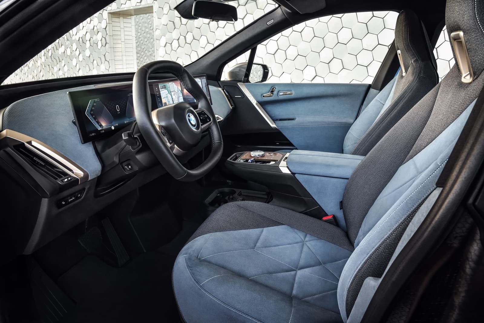 Vista lateral del elegante interior del BMW iX, mostrando asientos y tablero.