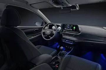 Vista del interior del Hyundai i20 con iluminación ambiental azul y diseño ergonómico.