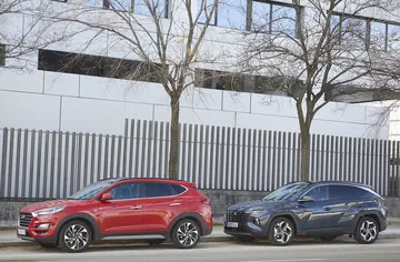 Vista lateral de dos Hyundai Tucson, uno rojo y otro gris, destacando su diseño