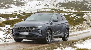 Vista lateral del Hyundai Tucson sobre terreno nevado, destacando su diseño robusto y moderno.