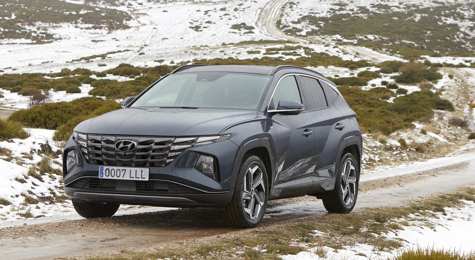 Vista lateral del Hyundai Tucson sobre terreno nevado, destacando su diseño robusto y moderno.