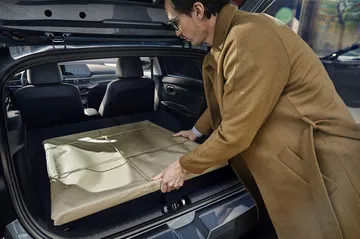 Imagen del maletero del Hyundai i20 con una persona cargando objetos. Capacidad y accesibilidad en primera plana.