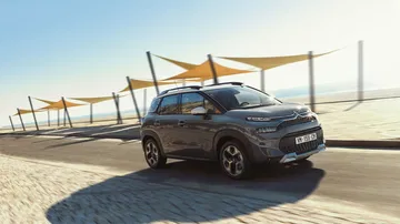 Vista lateral del Citroën C3 Aircross aparcado frente a una playa soleada.