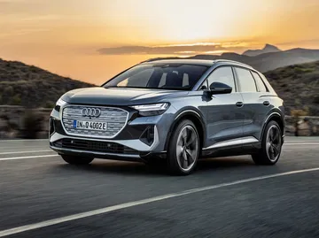 Audi Q4 e-tron capturado durante el crepúsculo, destacando su diseño frontal.