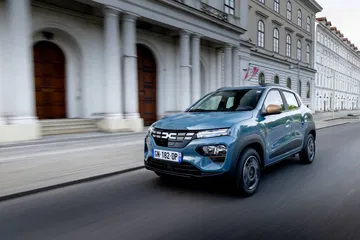 Vista dinámica del Dacia Spring en ambiente urbano mostrando su frontal y perfil.