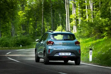 Vista trasera y lateral del Dacia Spring en un entorno natural.