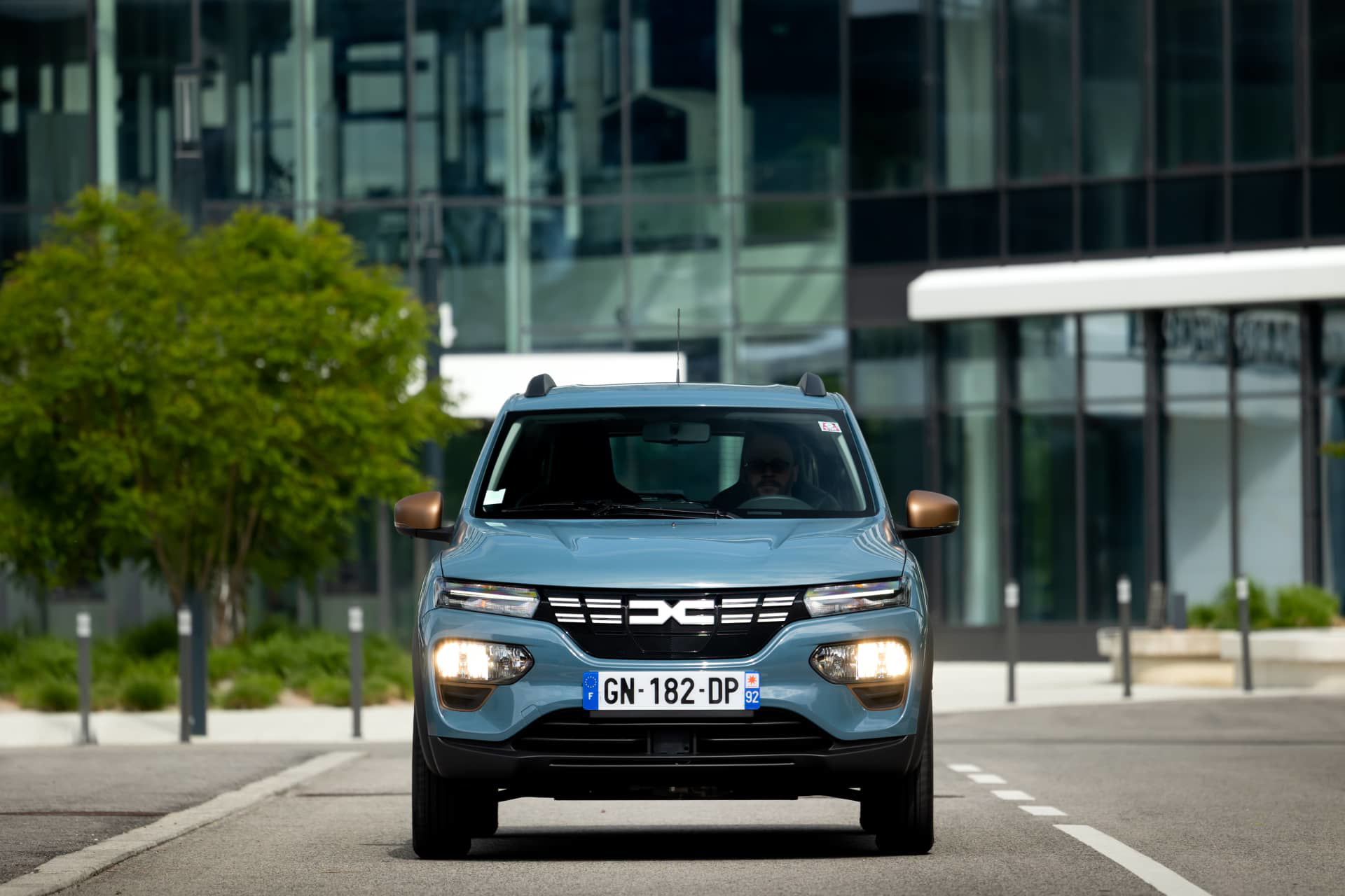 Vista frontal del Dacia Spring en entorno urbano, destacando su diseño accesible y moderno.