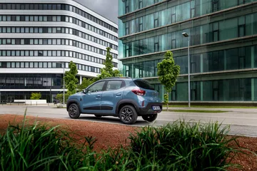 Vista lateral del Dacia Spring en un entorno urbano, destacando su diseño compacto.