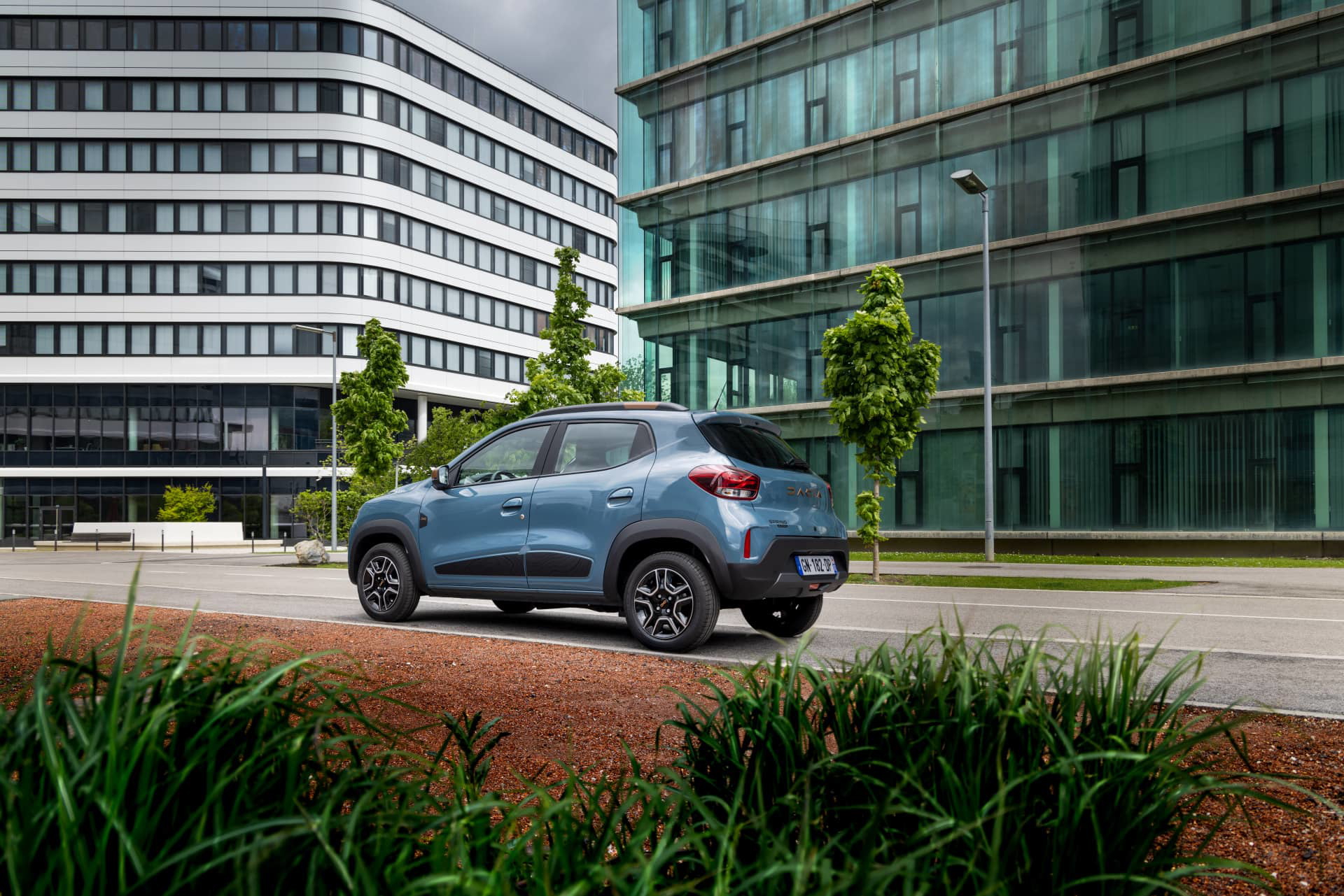 Vista lateral del Dacia Spring en un entorno urbano, destacando su diseño compacto.