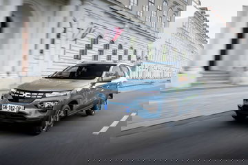 Vista dinámica del Dacia Spring en entorno urbano, destacando su frontal y lateral.