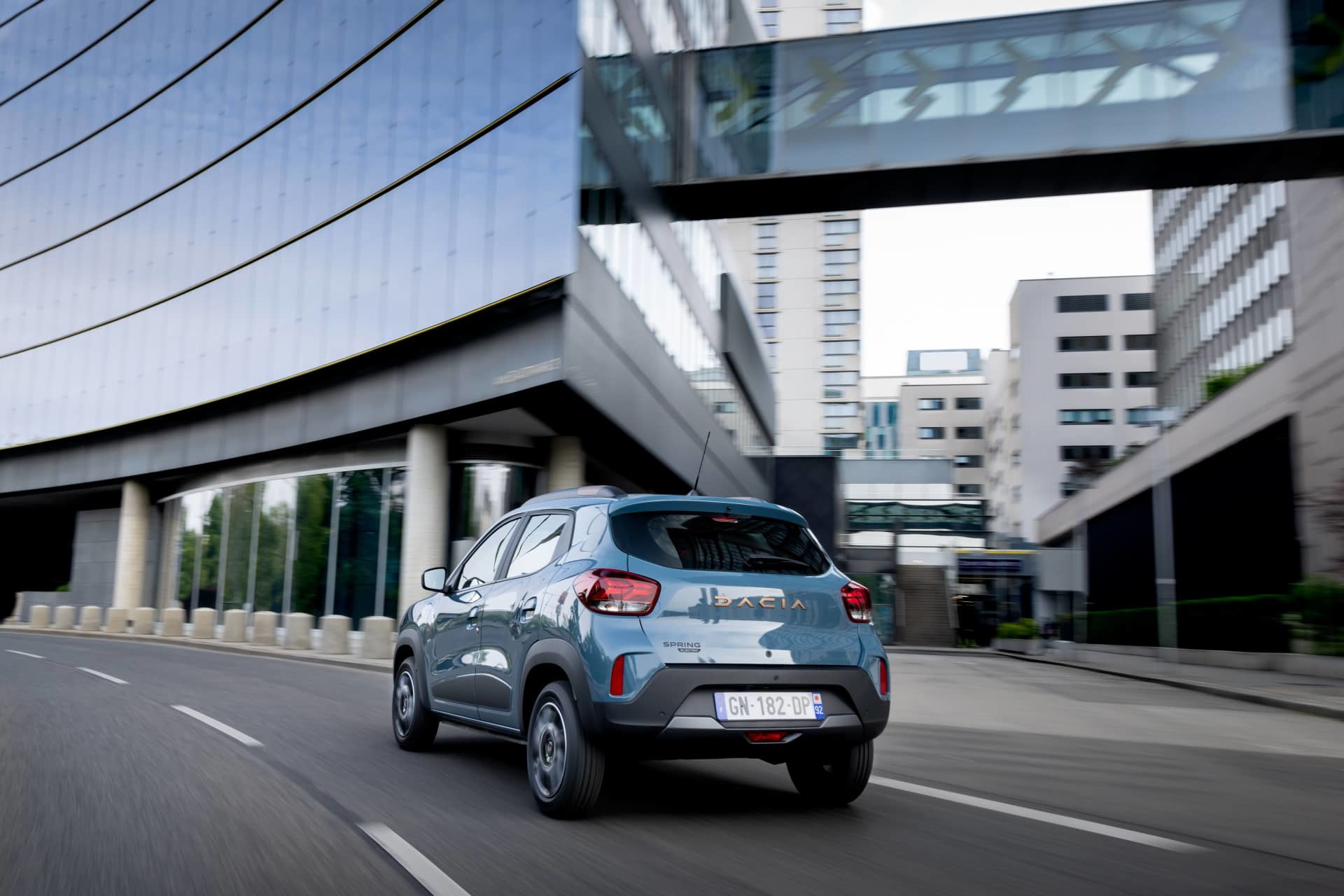 Vista dinámica del Dacia Spring en un entorno urbano, destacando su diseño frontal y lateral.