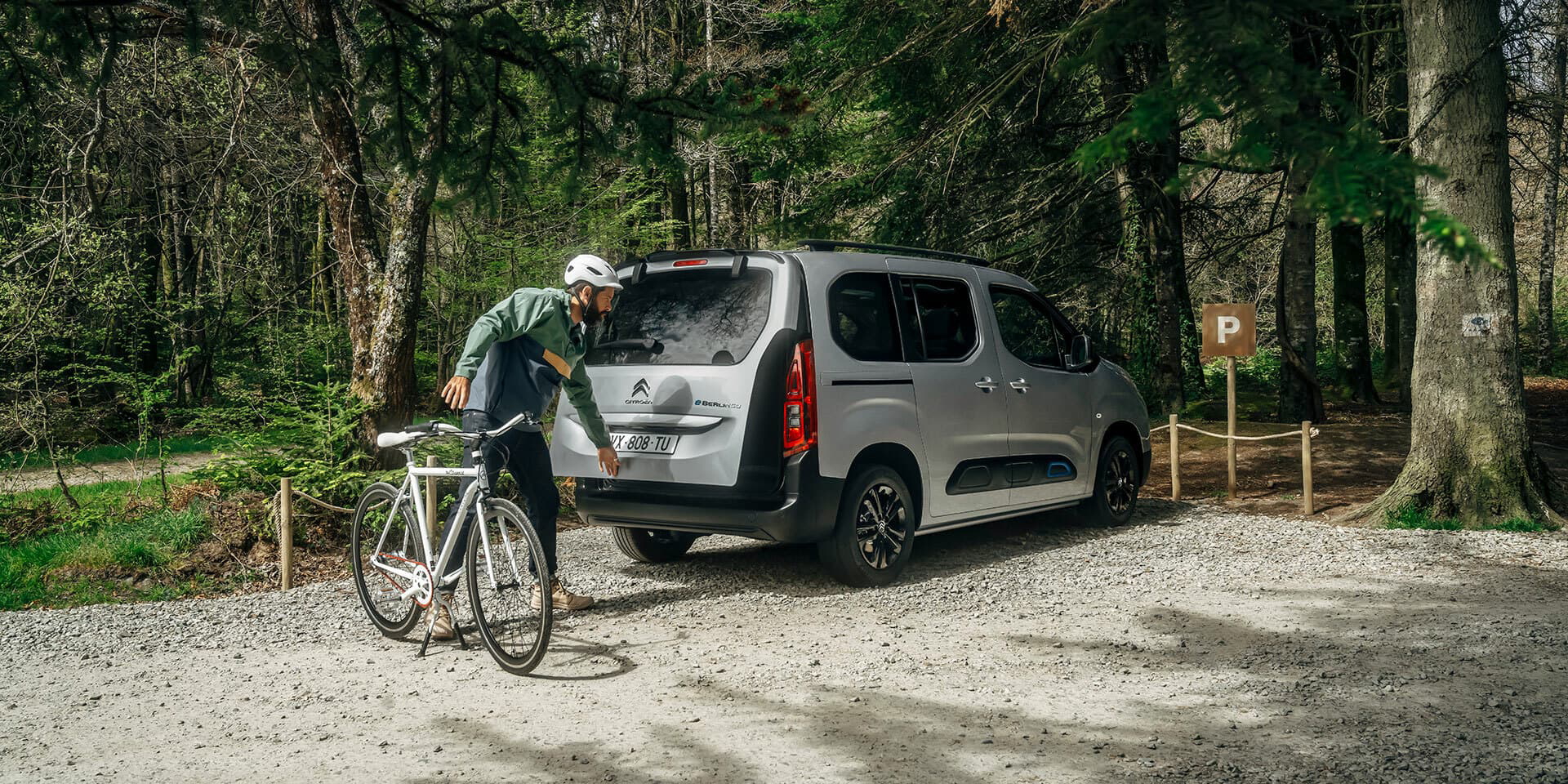 Vista trasera y lateral de un Citroën Berlingo con bicicleta en entorno natural.